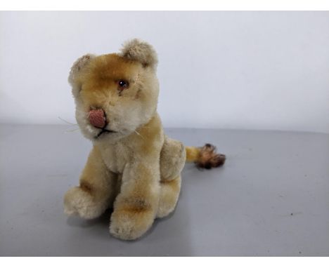 A Steiff Lea lioness soft toy, seated on its haunches, glass amber eyes, no label, 11cm h, 18 l 