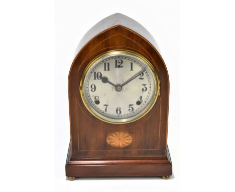 An Edwardian inlaid mahogany lancet topped mantel clock, the silvered dial with Arabic numerals above inlaid panel, raised on