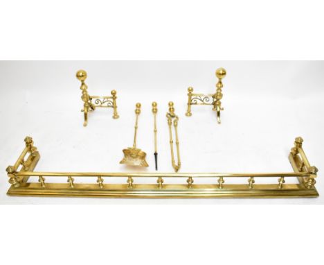 A group of brass metalware comprising fender, pair of fire dogs and a three piece companion set, width of fender 143cm, depth