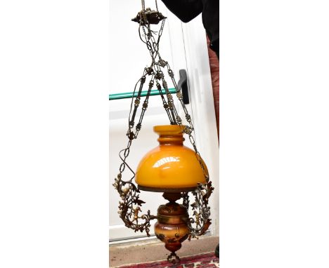 A decorative hanging oil lamp with amber coloured shade and ceramic reservoir, overall height 68cm.