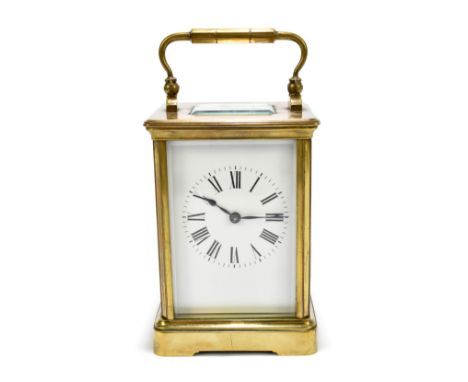 A circa 1900 French brass carriage clock with swing loop handle above white enamelled dial set with Roman numerals, the cased