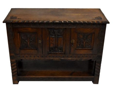 An early 20th century carved oak side cabinet, the moulded top above central carved panel flanked by twin cupboard doors rais