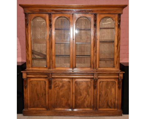 A Victorian mahogany four door bookcase, the moulded cornice above four arched glazed doors with base of three cushion moulde