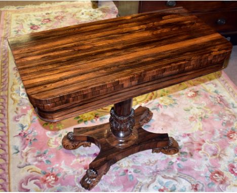 A William IV rosewood card table, with fold over swivel top, on a tapered column, platform and four carved scroll feet, heigh