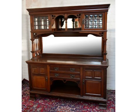 An Arts &amp; Crafts mahogany sideboard, the back section with a small rectangular mirrored plate flanked by two bow glazed d