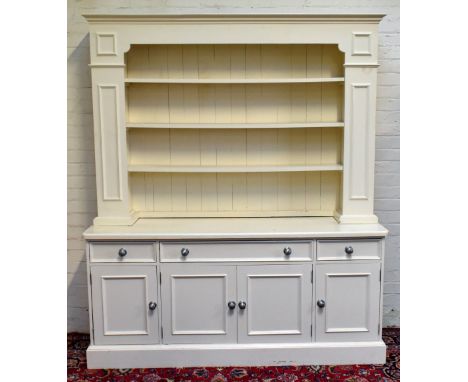 A modern cream painted pine New England style kitchen dresser with plate rack above three drawers and four panel cupboard doo