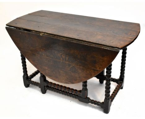 An 18th century oak oval drop-leaf gateleg dining table raised on bobbin turned and block supports and with twin end drawers.