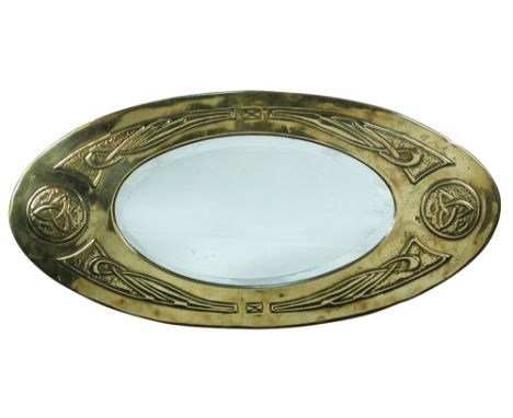 A Scottish School brass framed wall mirror, the oval bevelled glass with brass frame embossed with celtic motifs 30 x 61½cm (
