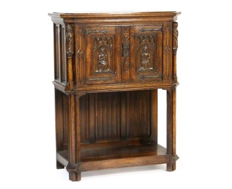 Gothic style carved oak cabinet on stand, early 20th Century, having two figural carved recessed panel doors opening to a sin