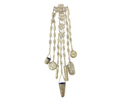 A Victorian metal chatelaine, the scrolling pierced and mask and putti decorated clip suspending seven chains with accessorie