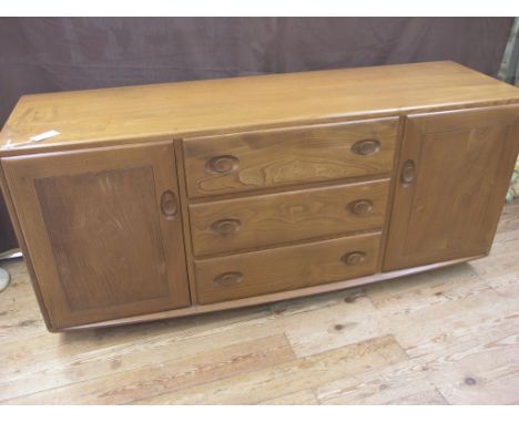 An Ercol golden elm sideboard, three central drawers and a cupboard to each side, 5ft. 1in.