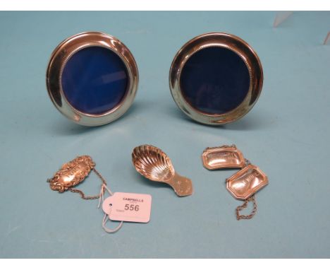 A pair of silver portrait photograph frames, 4.5in., a silver shell-shape caddy spoon and three silver wine labels