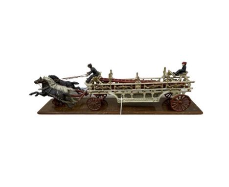 A complete reproduction cast iron fire cart with detachable ladder, orignal riders and three horses.