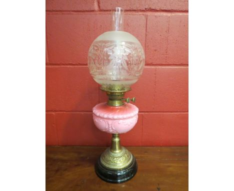 An ornate Victorian brass oil lamp, pink glass reservoir, etched shade