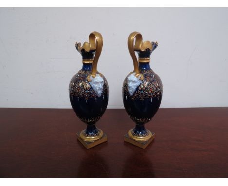 A pair of Royal Worcester urns in cobalt blue with gilt embellishment, mask handle (1 a/f)