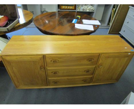 An Ercol Windsor sideboard No 455, design 1072 with three drawers flanked by twin cupboard doors, on a base, 26 6/8" x 51 2/8