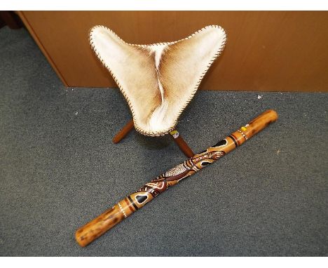 A foldaway tripod stand stool with detachable animal skin seat and a didgeridoo 98 cm (l)