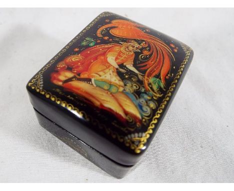 A small hinge lidded trinket box with lacquered decoration to the surface, red interior