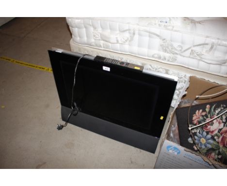 A Bang &amp; Olufsen television with remote control and a wall bracket