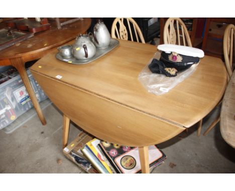 A light Ercol drop leaf dining table and three light Ercol stick back chairs 