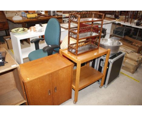 An oak tea trolley; together with a wicker hanging shelf; and a teak two door cupboard 