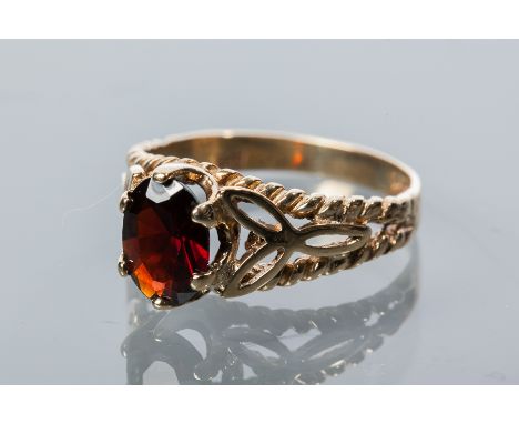 GARNET DRESS RING
set with a central oval cut garnet, on pierced shoulders, hallmarked for nine carat gold, size M-N