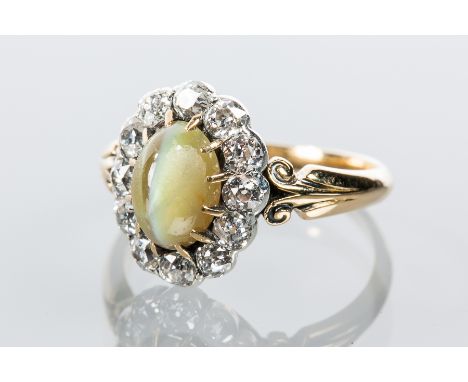 CHATOYANT GREEN GEM AND DIAMOND CLUSTER RING
the central oval cabochon cut green gem with cats eye effect, surrounded by rose
