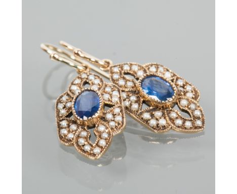 PAIR OF SAPPHIRE AND SEED PEARL DROP EARRINGS
of pierced scrolling form, each set with an oval sapphire, surrouned by a clust