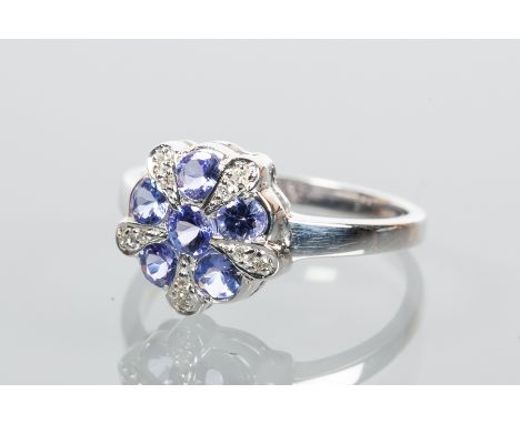 TANZANITE AND DIAMOND CLUSTER RING
of floral form, set with six tanzanites, surrounded by brilliant cut diamonds, in nine car