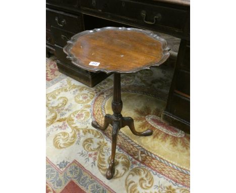 A circular mahogany wine table with pie crust edge standing on a tripod base 