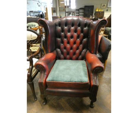 A Georgian style wing back easy chair in buttoned red leather  