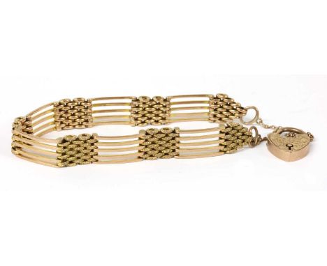 A gold five row gate bracelet, plain bars with textured links between, to heart shaped padlock clasp and safety chain, tested