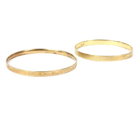 A gold bangle, with engine turned decoration, marked 9ct, 14.24g, together with a 9ct metal core bangle, 18.89g (2)