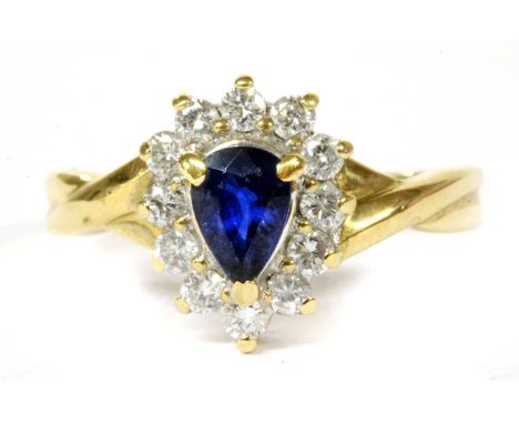 A gold sapphire and diamond cluster ring, with a pear mixed cut sapphire, claw set, to surround of brilliant cut diamonds, wi