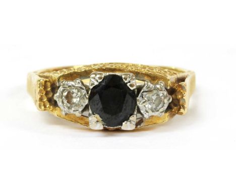 An 18ct gold sapphire and diamond three stone ring, an oval mixed cut sapphire with a brilliant cut diamond at each side, all