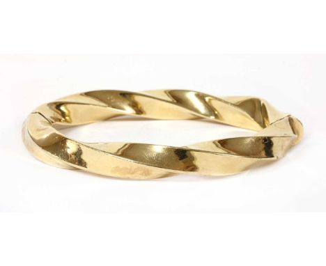 A gold hollow oval hinged bangle, square section twisted wire, with concealed clasp and internal wire safety, tested as appro