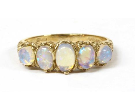 A 9ct gold five stone opal ring, a graduated row of oval and round cabochon opals, claw set to scrolling shoulders and a D se