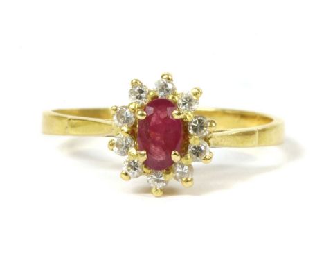 A French gold ruby and paste cluster ring, an oval mixed cut ruby to surround of round paste, all claw set to a wire gallery,