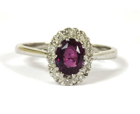 An 18ct white gold purple sapphire and diamond cluster ring, an oval mixed cut purple sapphire with a stated weight of 1.06ct