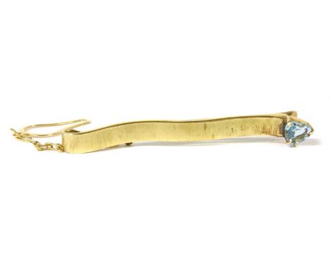A gold aquamarine tie slide, a heart shaped mixed cut aquamarine, claw set to one end of the slightly undulating bar, with ch