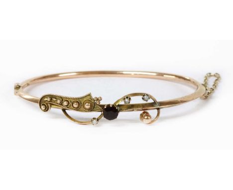 A hollow gold garnet and split pearl bangle, a circular mixed cut garnet claw set to the top half, to wire scroll claw set wi