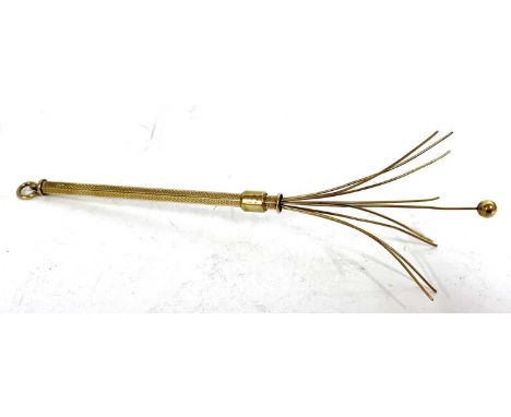 A 9ct gold swizzel stick cocktail stirer, the hexagonal barrel with engine turned decoration, and sliding mechanism suspended