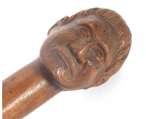 A vintage carved hardwood walking stick, carved with a mans head having a moustache and Maori type facial tattoos, shaft brok