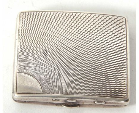 An Art Deco ladies compact, square form with a radial engine turned decorated front, push button opening to a plate stamped V