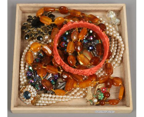 A tray of costume jewellery including coral effect bangle and amber effect necklace etc.
