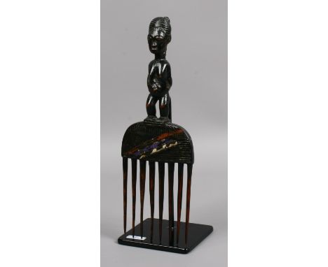 A tribal art figural hair comb on stand.