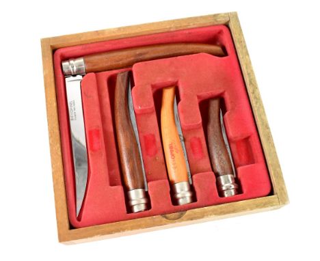 An Opinel shop counter display knife set comprising four country pursuit knives of graduated sizes, in a glazed wooden presen