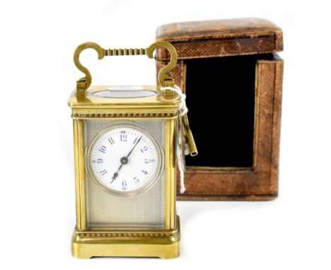 An early 20th century brass carriage clock, the circular dial set within an engine turned surround, the white dial set with b