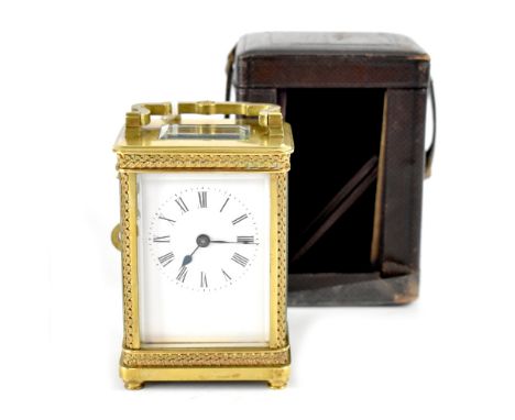 An early 20th century French brass carriage clock with ornate filigree decoration to sides, top and base, the white dial set 