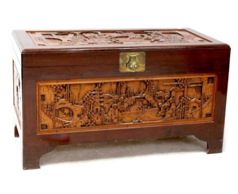 A Chinese camphor wood blanket box with carved panels depicting figures within landscapes, on bracket feet, height 57cm, widt
